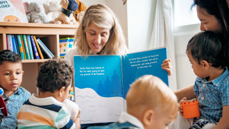 Woman reading picture book to toddlers